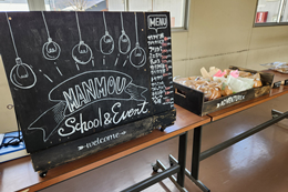 岡谷南高校の校内で昼食販売を行う「マンモウ食堂」の黒板ボードと、販売台に並べられたパンや弁当。