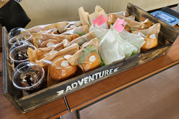 岡谷南高校の昼食販売で用意された、ボリュームたっぷりのチキンカツパンやホイップクリームサンドが並ぶ様子。