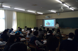 岡谷南高校の授業参観の様子。教室でプロジェクターの資料を使いながら授業を行う教員と、机に向かって学習に取り組む生徒たち。