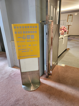 岡谷南高校吹奏楽部「第62回定期演奏会 一心響音」の案内看板。カノラホール小ホールの入口に設置された、黄色の背景が目を引く公演ボード。