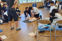 岡谷南高校の普通救命講習にて、救命用の人形（トレーニングマネキン）を使用して胸骨圧迫の実習を行う生徒の様子。