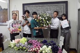 JA信州諏訪から贈られた花束を受け取り、生徒と関係者が記念撮影をしている様子