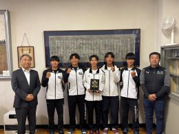 岡谷南高校の校長室にて、優勝盾を手に校長先生・顧問の先生と笑顔で記念撮影を行う漕艇部のメンバー