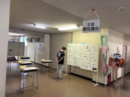 岡谷南高校の教室内で、パネル展示や学習発表資料を熱心に読み込む一般来場者の様子