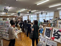 岡谷南高校の図書室にて、多くの本やおすすめ紹介のポップに囲まれて賑わう来場者たち