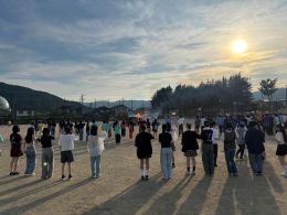 岡谷南高校の夕暮れのグラウンドで、生徒たちが輪になって踊るフォークダンス