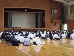 岡谷南高校の体育館で、ステージ上の担当者の話を真剣に聞く1・2年生の講座選択説明会の様子