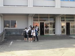 岡谷南高校の校舎玄関前で、スタッフから選挙啓発資料を受け取る生徒たち