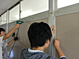 岡谷南高校：完成間近の掲示板。書道や美術などの生徒作品を掲示できるよう、フレームの歪みがないか確認しながらネジ止めを進めている作業風景。