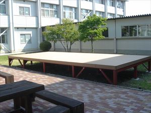 岡谷南高校：中庭に完成した常設ステージの全景。南高祭などのイベント活用に向けて整備され、周囲のインターロッキングやベンチと調和した広々としたスペース。