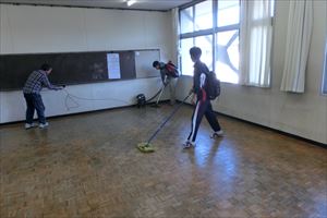 岡谷南高校：掃除機とモップを使い、教室の床からほこりやゴミを徹底的に取り除いている準備作業の風景。