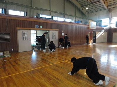 岡谷南高校：広い大体育館の端から端まで、生徒たちが分担して床の汚れを丁寧に拭き取っている作業風景。