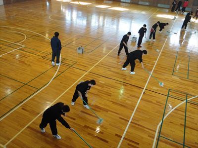 岡谷南高校：専用のモップを使い、光沢が出るよう均一に床へワックスを塗り広げている生徒たちの様子。