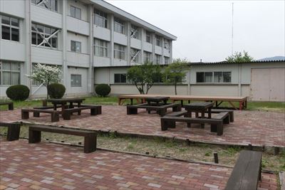 岡谷南高校：中庭に設置された、塗装メンテナンス済みの木製テーブルとベンチのセット。