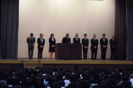 岡谷南高校の新任式で、ステージ上に並んだ新任の先生方が全校生徒に向けて紹介されている場面。